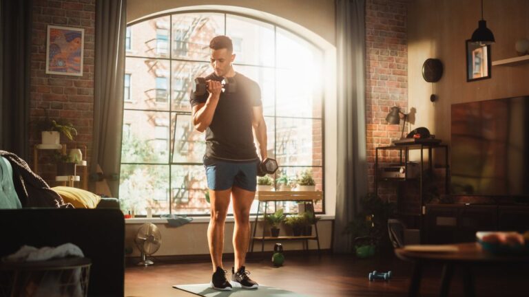 Man performs biceps curl with dumbbells in living room