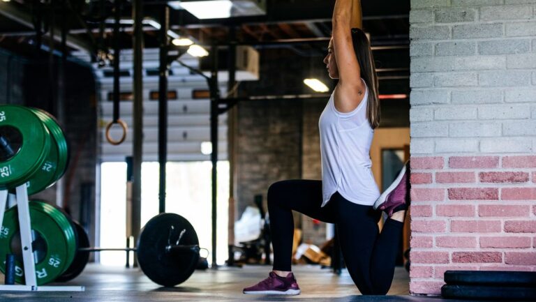 Woman performs couch stretch in gym