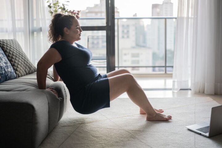 Woman uses couch to perform triceps dips at home