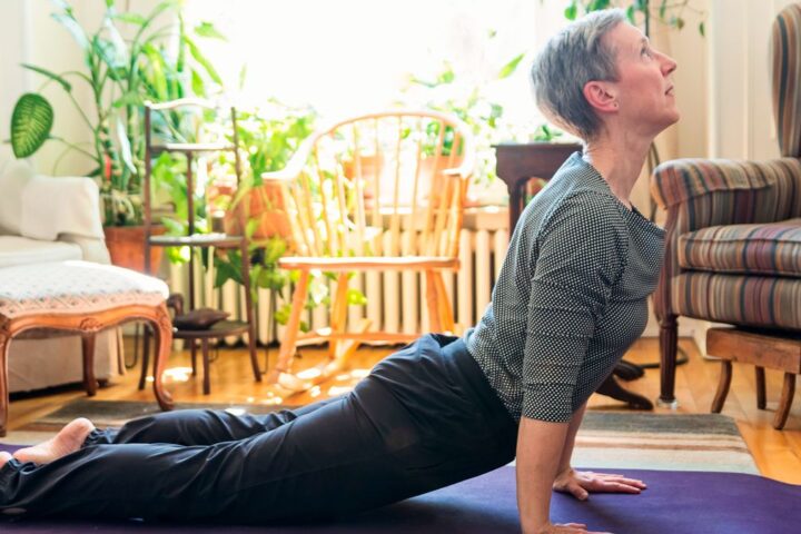 Woman performs swan Pilates move at home