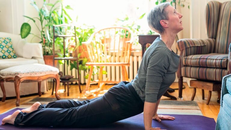 Woman performs swan Pilates move at home