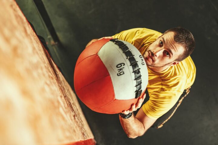Man seen from above about to throw a large 6kg medicine ball up