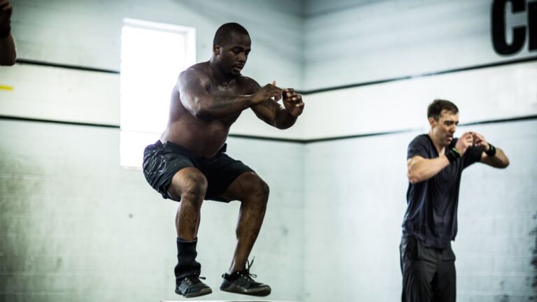 A man performing a box jump during a CrossFit workout